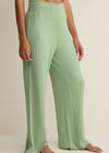 Green ribbed pants worn by a person on a beige background