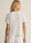 Woman wearing a white ribbed t-shirt and shorts set on a beige background