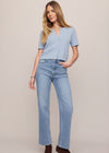 Woman wearing a light blue top and jeans on a plain background