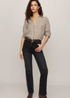 Woman wearing a checkered shirt and black jeans on a plain background