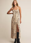 Woman wearing a leopard print slip dress with black boots on a beige background