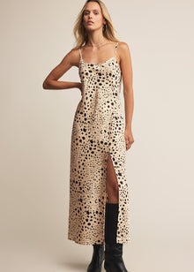  Woman wearing a leopard print slip dress with black boots on a beige background