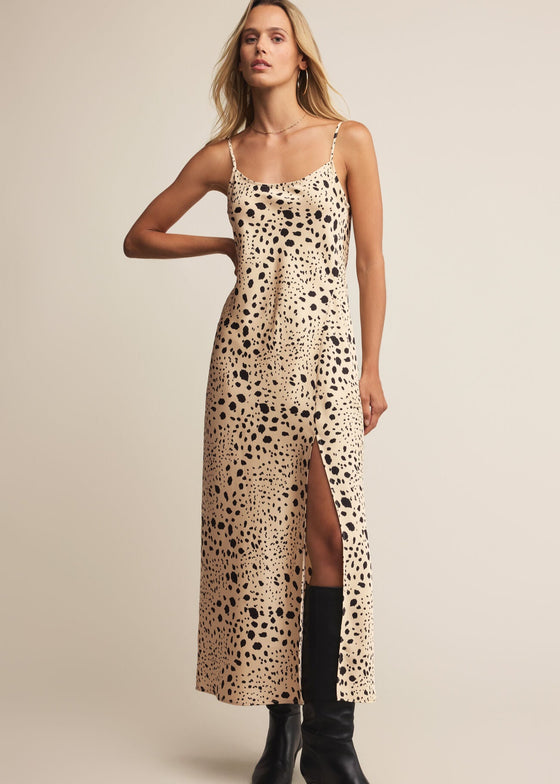 Woman wearing a leopard print slip dress with black boots on a beige background