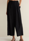 Person wearing black wide-leg pants on a beige background