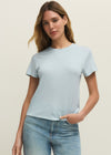 Woman wearing a light blue t-shirt and jeans against a beige background